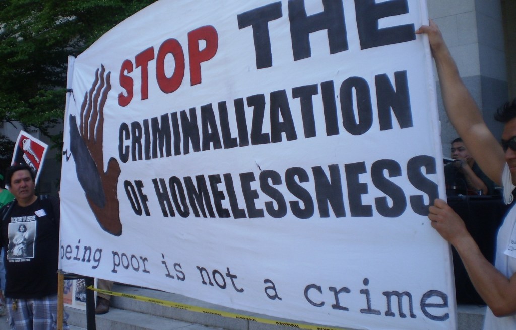 Sign that says "Stop the criminalization of homelessness. Being poor is not a crime.